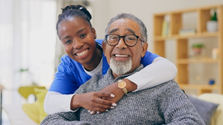 Long-term caregiver and senior man smiling together