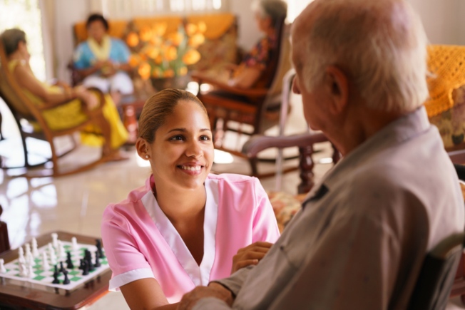 Caregiver kneeling by senior man providing premier care in Ruston, LA