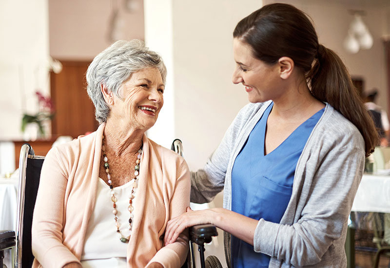 Elderly woman and nurse talk in a skilled nursing facility dining room in Ruston, LA