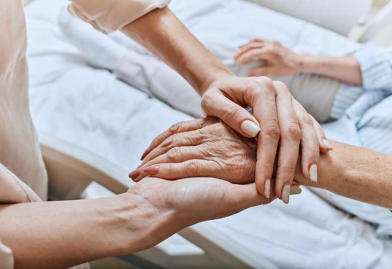 Woman holds the hand of a relative in hospice care in Ruston, LA
